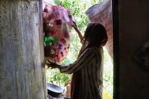 a woman holding a bag of empty plastic bottles