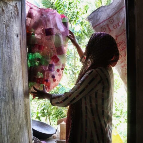 a woman holding a bag of empty plastic bottles