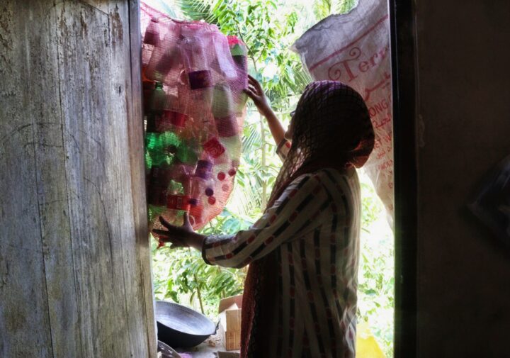 a woman holding a bag of empty plastic bottles