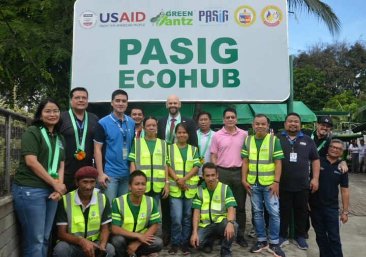 A group of people, some in high-visibility vests and some in normal clothes, pose for the camera in front of a sign that reads 