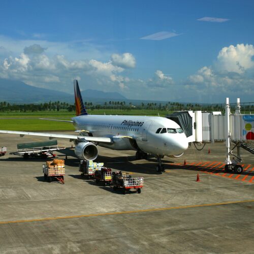 Image from an airport concourse of an Philippines Air airplane connected to a skybridge.