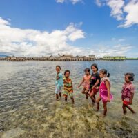 Children make the most of a calm day at Torosiaje village to forage for sea food. Sulawesi, Indonesia.