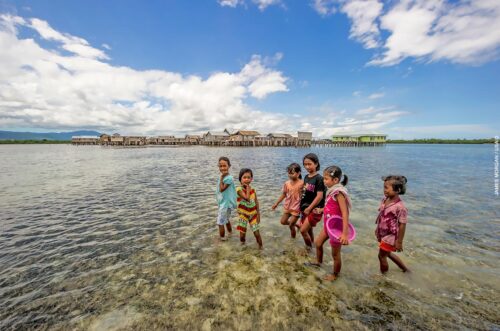 Children make the most of a calm day at Torosiaje village to forage for sea food. Sulawesi, Indonesia.