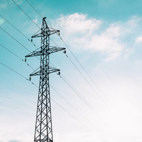 Generic image of high-voltage power lines connected to a tower and disappearing into the distance.