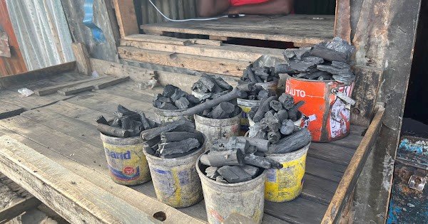 Several buckets full of wood charcoal sit in the foreground.