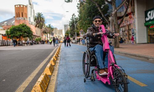 A man rides an electric bike toward the camera in a protected bike lane in central Bogotá.