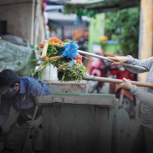 Two men use hand tools to collect and separate garbage.