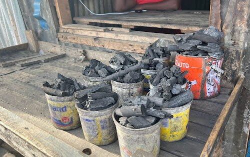Several buckets of wood charcoal sit on a deck.