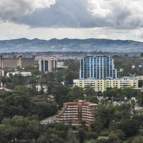 The city of Nairobi stretches across the foreground to the base of a mountain range that dominates the background. Storm clouds dot the sky. Credit: Ninara (Flickr)