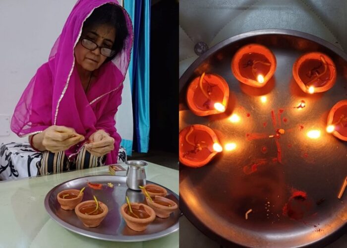 A woman lights red tea candles that are placed on a metal platter.