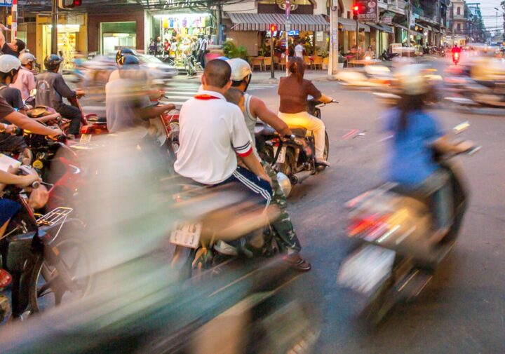 A blur of people on motorbikes on a Vietnam street moves from lower left to upper right in the frame.