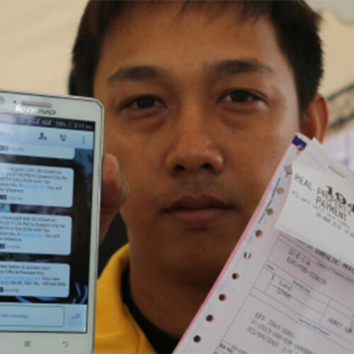 A man looks into the camera and displays his mobile phone and a payment receipt.