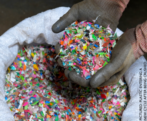 two gloved hands holding a handful of small, plastic pieces.