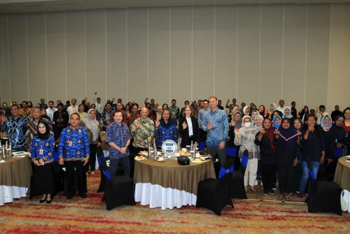 A large group of event attendees stand together and smile at a camera.