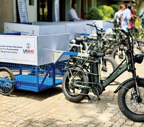 Photo of an electric assist bicycle with a small trailer attached to the back.