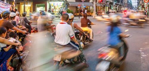 Image: Motorbikes zoom by in a blur on a busy street in Vietnam.