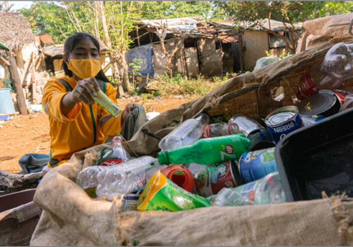 Christine, an Eco-Warrior, sorts through waste in Puerto Princesa City, Philippines wearing her new uniform co-created and provided through a USAID-supported grant to Project Zacchaeus.